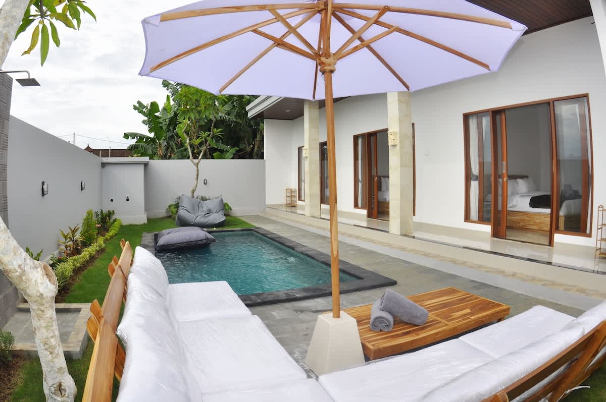 Exquisite outdoor seating crafted from premium teak wood, complemented by a stylish umbrella and cozy bean bags. Thoughtfully arranged by the pool, this setup creates the perfect blend of comfort and elegance for a serene oasis experience.